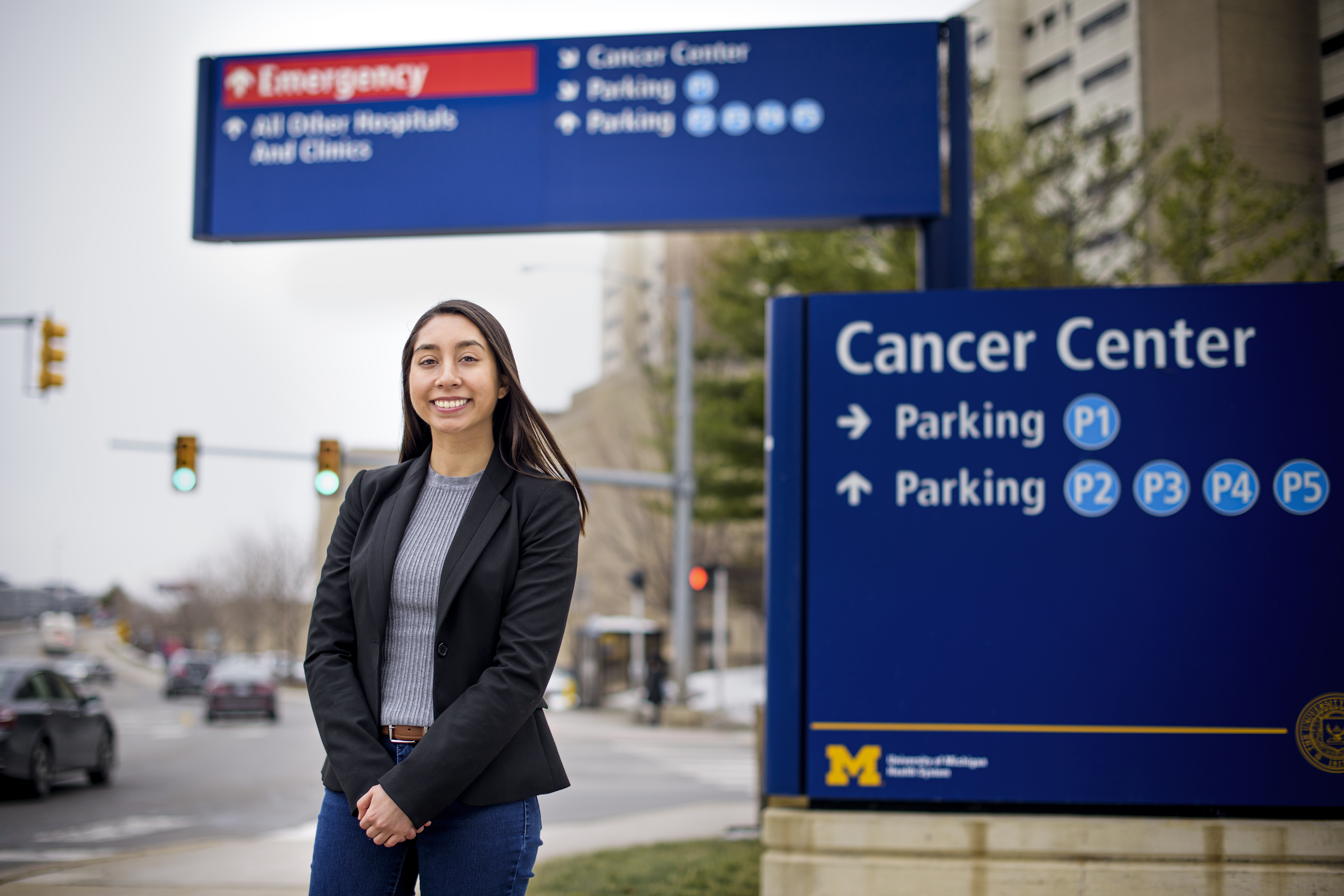 A student standing next to a sign that says "Cancer Center parking."