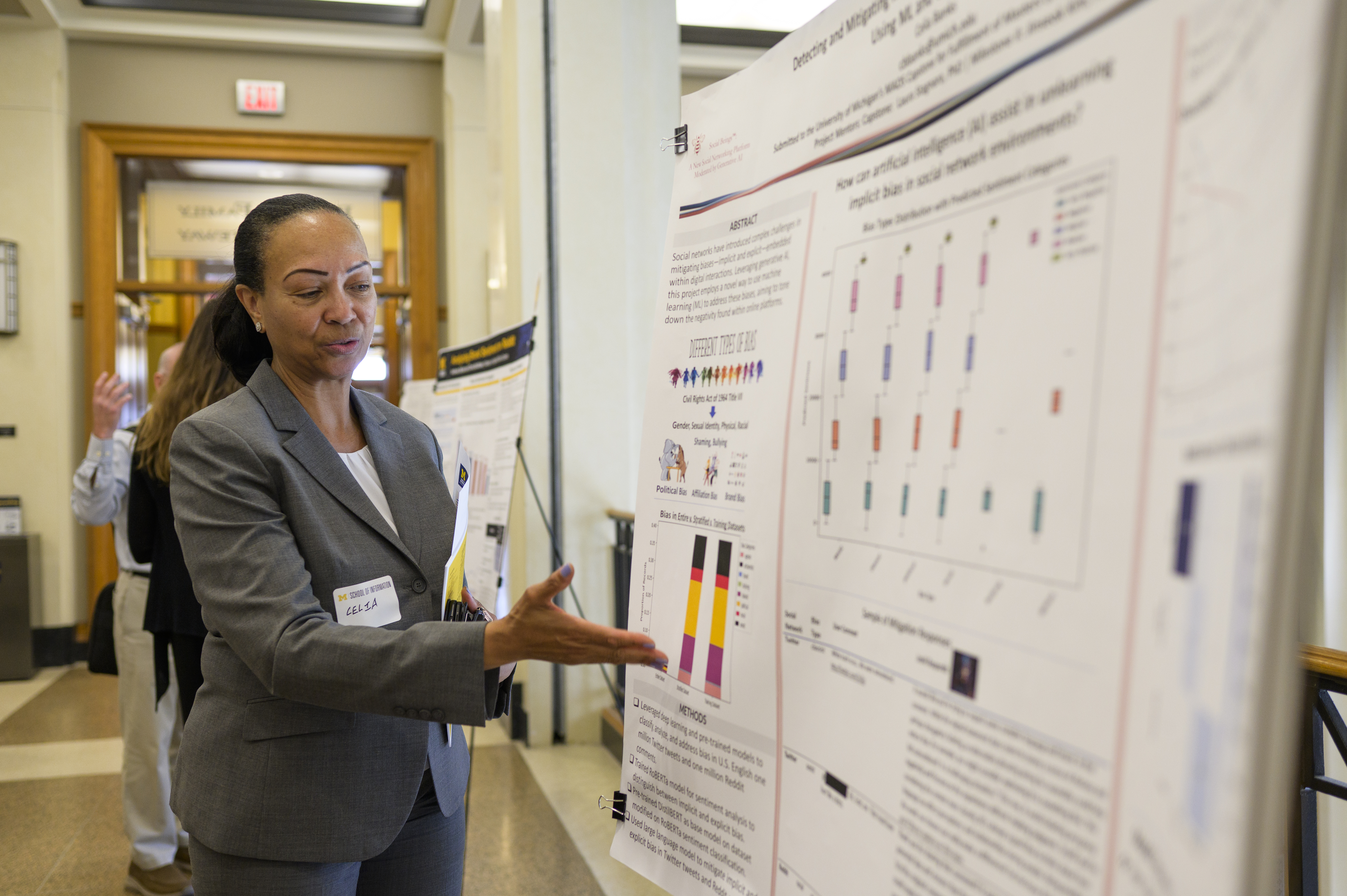 A student talking and gesturing at a research poster.