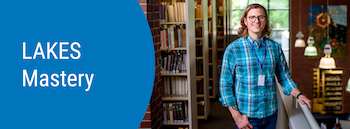 A student standing in a library next to bookshelves. Text on the image says LAKES Mastery.