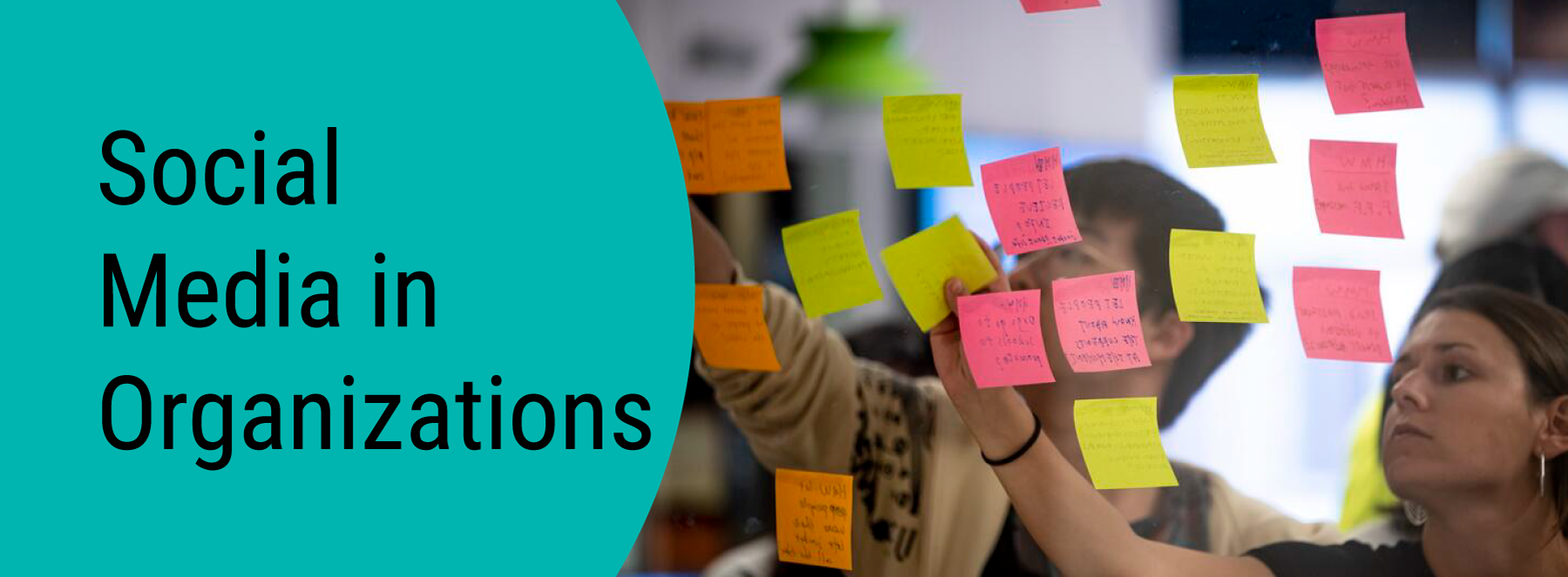 Social Media in Organizations. People putting sticky notes up on a clear wall.
