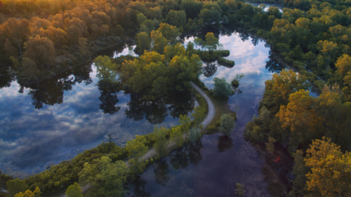 An image of an aerial view of a river in Otisville, Michigan, with clouds reflected in the surface of the water.