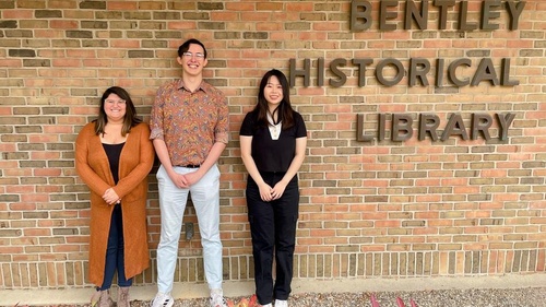 Three students standing in front of a sign that says Bentley Historical Library