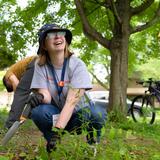 A UMSI student holds a shovel and smiles while working in a rain garden 