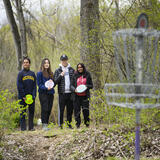 Master of Science in Information students Suviksha Hirawat, Rebekah Lim, Terrence Liu and Yeshashree Prasanna pose with their prototype of “DiscGuide,” an auditory disc golf experience for visually impaired users April 2023 at the City of Ann Arbor Bandemer Disc Golf Course.