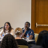 Two people on a panel in front of a crowd.