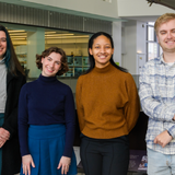 Four students posing together and smiling.