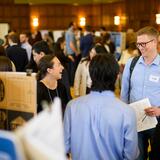 A group of students and faculty chatting at a poster fair.