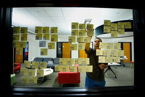 man sticking post-it notes onto a window