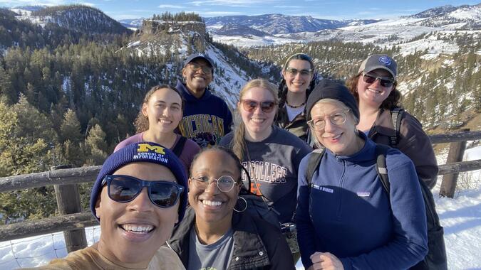 A selfie of eight individuals posing at an overlook in Yellowstone National Park