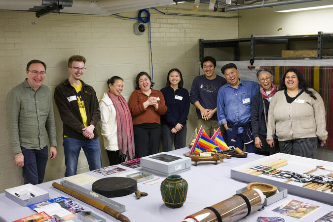 Students and community members pose, laughing, around a table covered in Filipino community archival materials