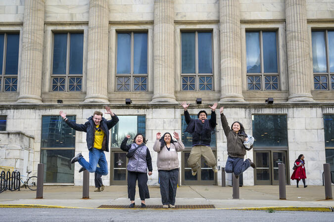 Five students jump in the air on a Chicago street