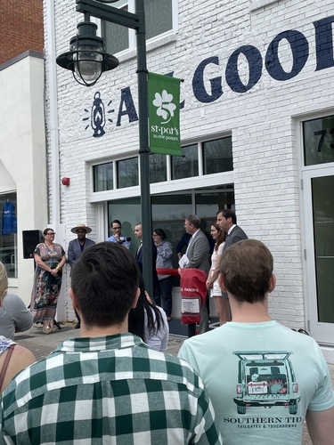 A crowd gathers outside of a bookstore for a ribbon-cutting ceremony.