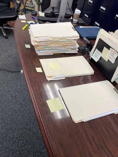 Stacks of folders and papers on a desk.