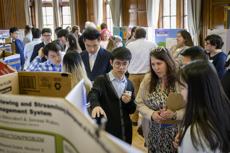 Students look over posters in a conference room