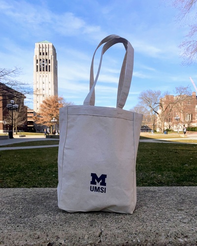 A photo of the UMSI logo on the back of the tote bag designed by Avalon Hu, with the Burton Memorial Tower visible in the background