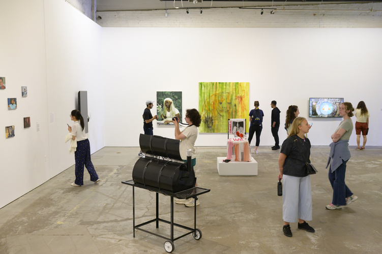 Scattered people stand in an art gallery, viewing different pieces