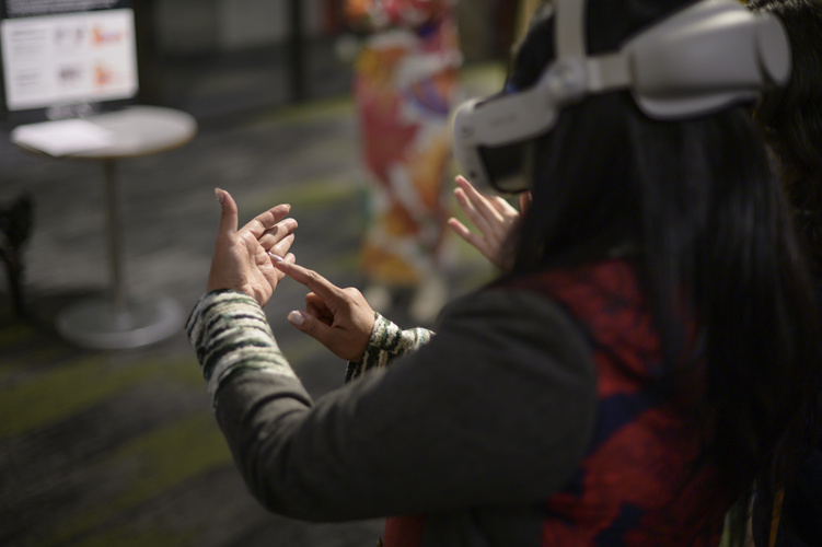 A person in a headset runs their finger along their palm, copying the movement of another person's hand