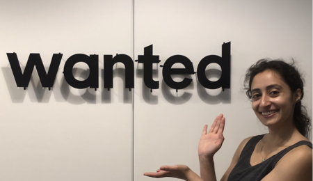 Salma Siddiqui posing next to a sign displaying the "wanted" logo.