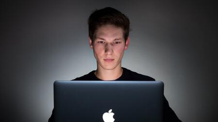 A man using a laptop, lit by the glow of the screen