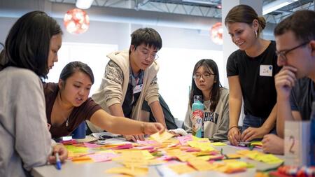 Students Gathered around a table filled with sticky notes