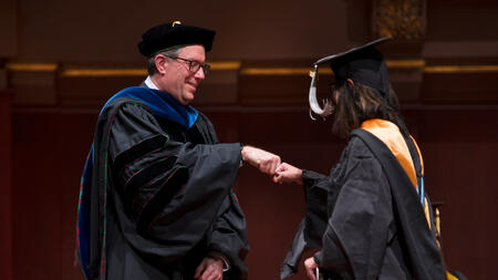 Thomas Finholt fist bumps a student during the graduation ceremony.