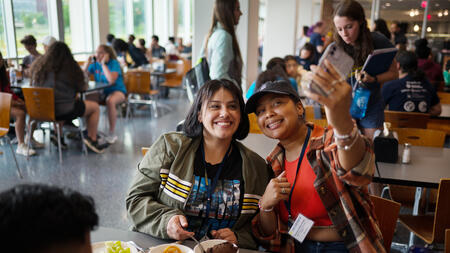 Community college students Deisy Magana and Yessenia Satana Perez take a selfie while eating dinner at the Mosher-Jordan Dining Hall during the UMSI Community College Summer Institute program on Monday, June 6, 2022.