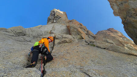 Matthieu Lienart looks over his shoulder as he climbs the face of a mountain. 
