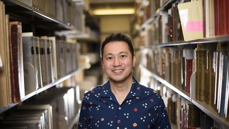 Ricky Punzalan smiling and standing in between two bookshelves. 
