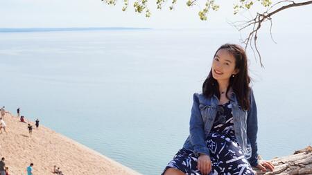 Yi Mao sitting on a tree overlooking a beach