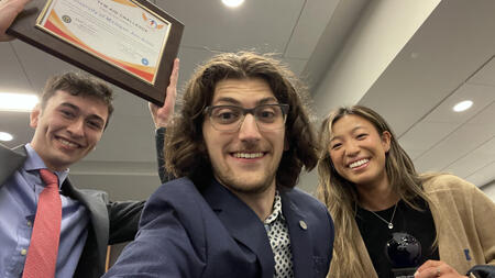 A selfie of three students posing with awards 