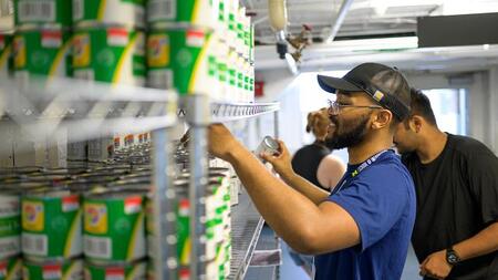People stacks cans on a shelf full of similar cans
