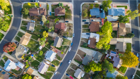 A landscape photo of a suburban neighborhood taken from above featuring a row of houses. 