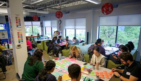 Students working together at tables covered in sticky notes