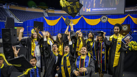 A group of students in graduation regalia throwing their mortar boards in the air.