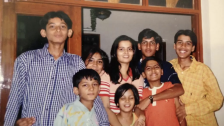 Eight cousins pose together for a photo, with a young RJ Jain wearing an orange shirt