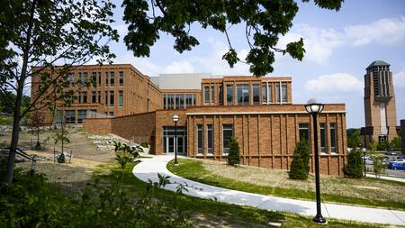 The Leinweber Computer Science and Information Building and the Lurie Bell Tower framed by trees in the foreground.