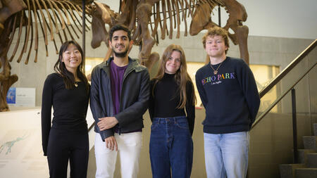 Four students standing in front of an animal skeleton in a museum