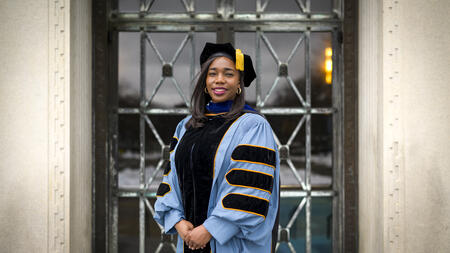 A student wearing full graduation regalia for a doctoral student.