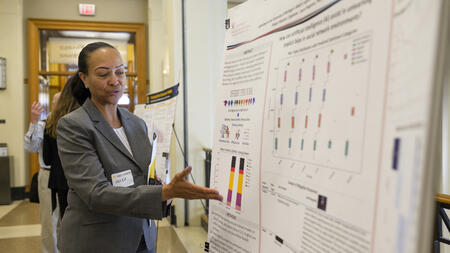A student talking and gesturing at a research poster.