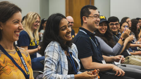 A seated row of students chuckle, all wearing lanyards