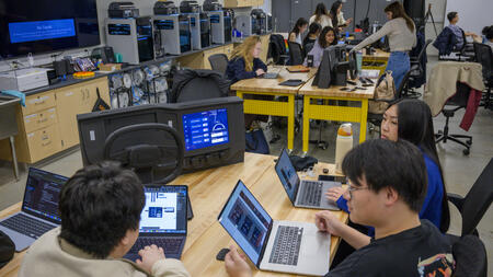 A group of students on laptops in a maker lab.
