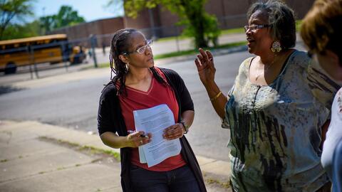 Tawanna talking to a woman in front of a school