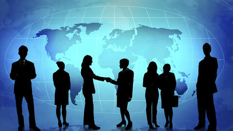 The silhouettes of people dressed in business attire and holding briefcases shaking hands. Overlaid on a map of the world.