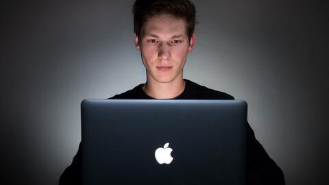 A man using a laptop, lit by the glow of the screen