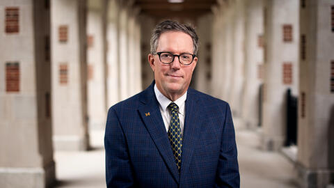 UMSI Dean Thomas A. Finholt standing beneath the arches in the North Quad courtyard