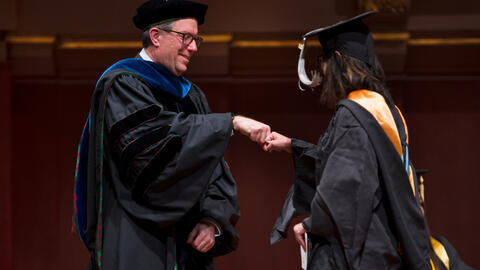 Thomas Finholt fist bumps a student during the graduation ceremony.
