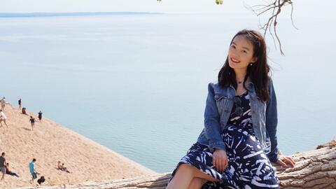 Yi Mao sitting on a tree overlooking the beach