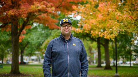 A photo of Kyle Bylin standing on campus with fall foliage behind him.