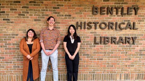 Stephanie Vettese, Clayton Zimmerman and Ziyan Zhou stand in front of the brick exterior of the Bentley, which reads "Bentley Historical Library"