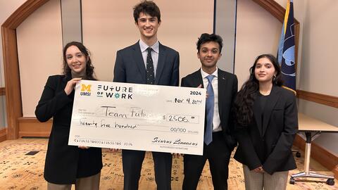 Four members of the winning team pose with a giant check made out to Team Future